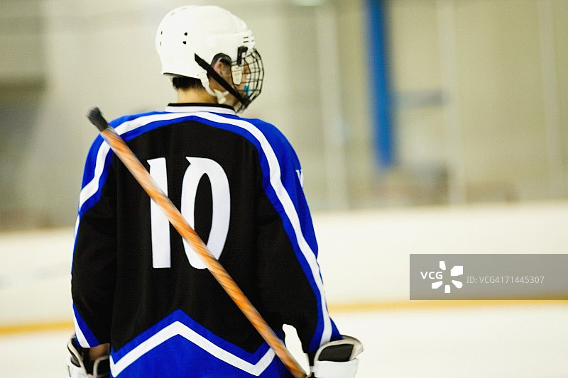 手持冰球杆的冰球运动员背影图片素材