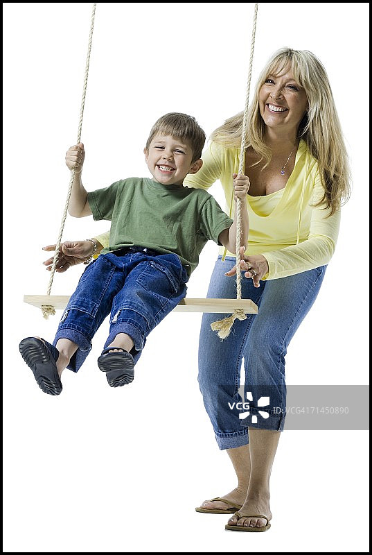 母亲在秋千上推着儿子图片素材