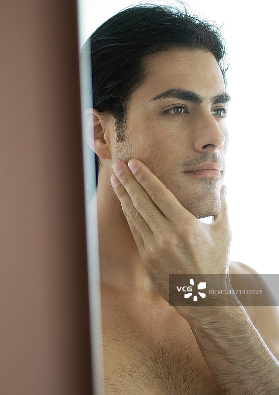 照镜子摸脸颊的男人图片素材