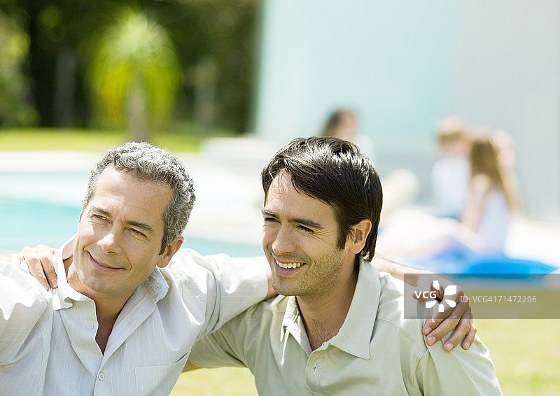 两个男人搂着对方的肩膀，面带微笑图片素材