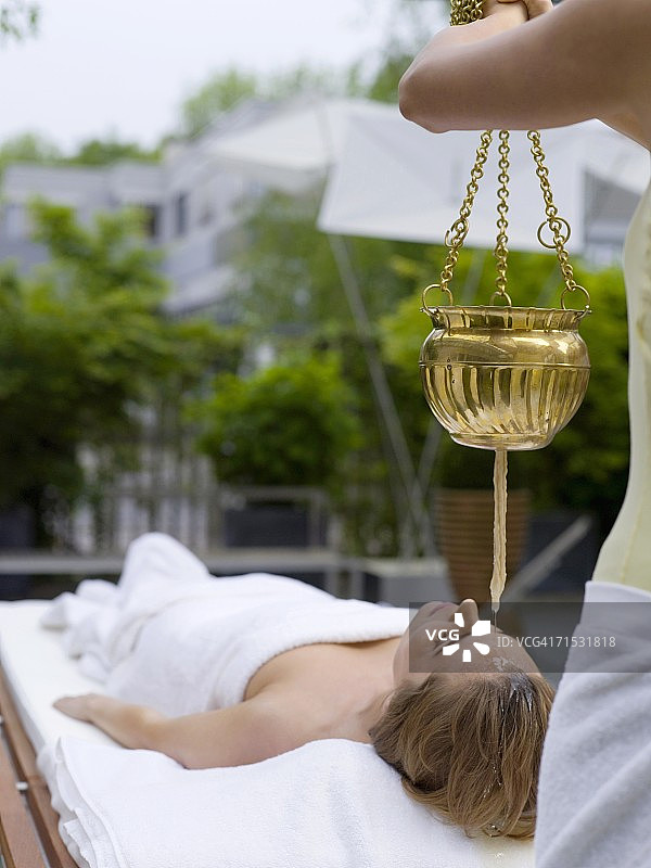 年轻女子在水疗中心做头部精油护理图片素材