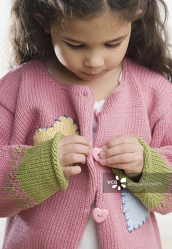 正在扣毛衣的年轻西班牙裔女孩图片素材