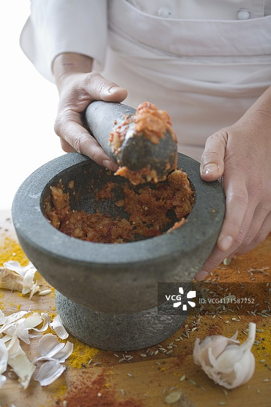 厨师用研钵和研杵研磨大蒜、马沙拉酒和姜黄图片素材