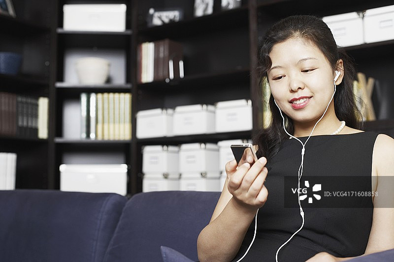 年轻女子戴着耳机听音乐微笑的低角度景观图片素材
