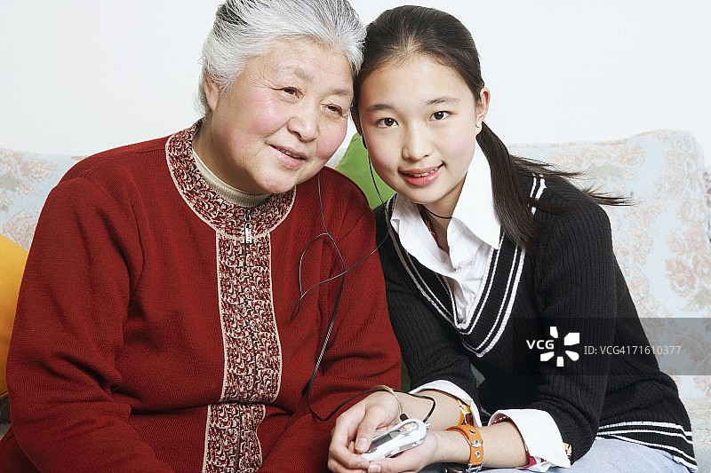 与祖母分享耳机的年轻女子肖像图片素材