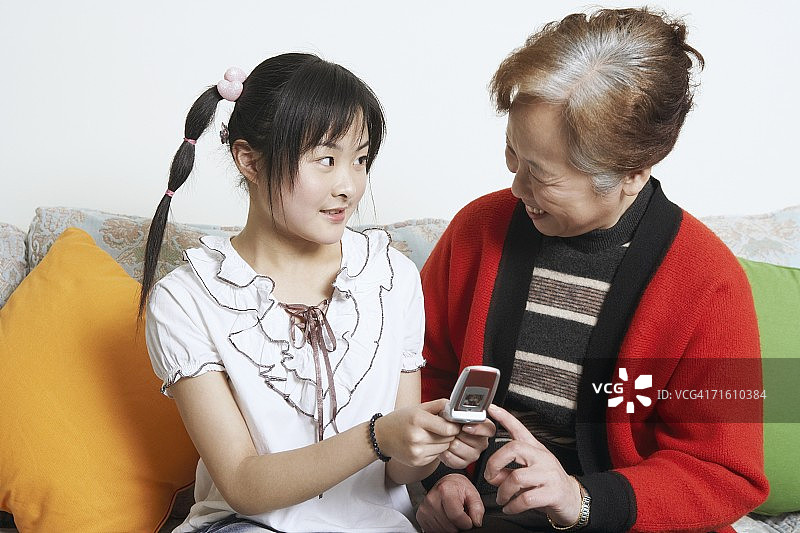 年轻女人面对祖母，手持手机图片素材