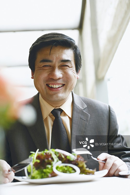 商务人士坐在餐厅的桌旁微笑的肖像图片素材