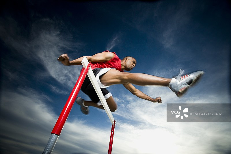 低角度拍摄的年轻男子跨越障碍赛跑图片素材