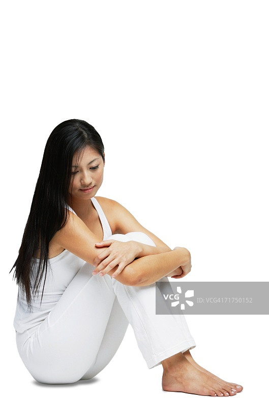 女人坐在地板上，抱着膝盖向下看图片素材