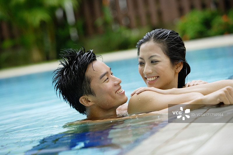 在游泳池里互相微笑的情侣图片素材