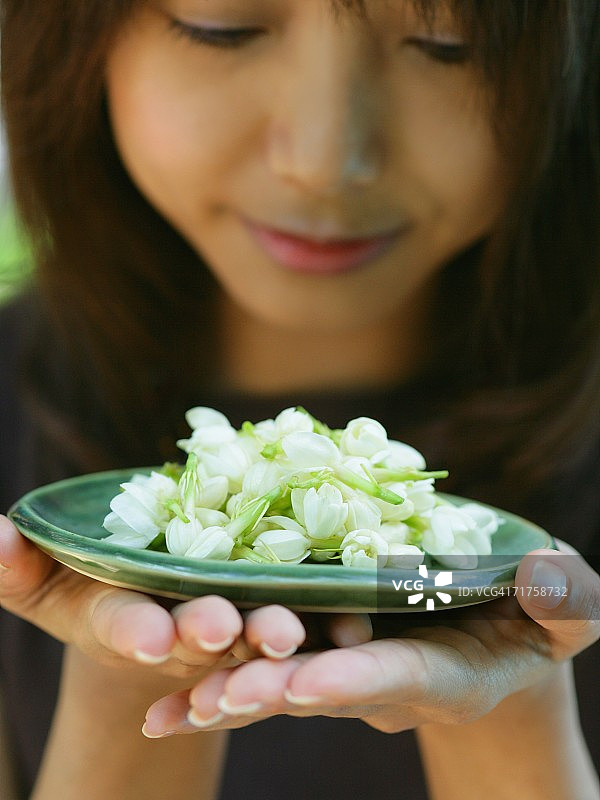 年轻女人手捧茉莉花盘的特写图片素材