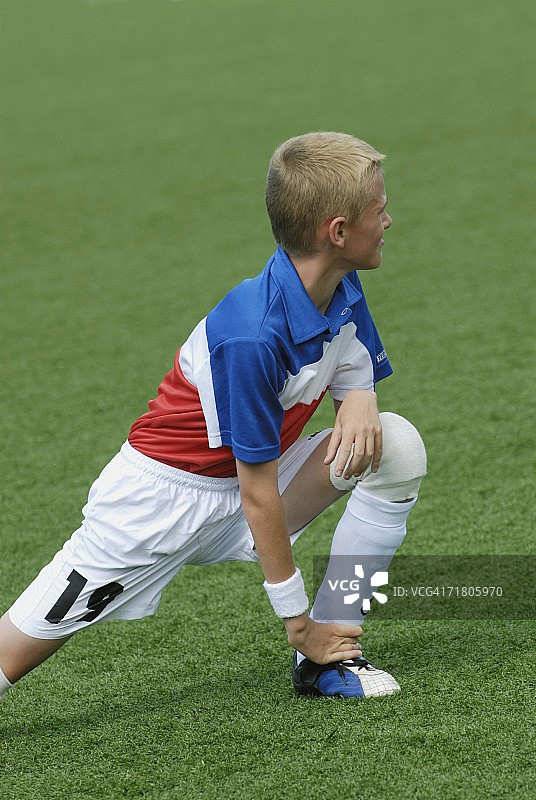 足球运动员在足球场上伸展身体图片素材