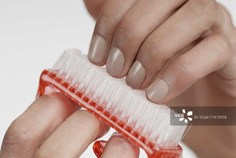 女人用刷子刷指甲的手部特写图片素材