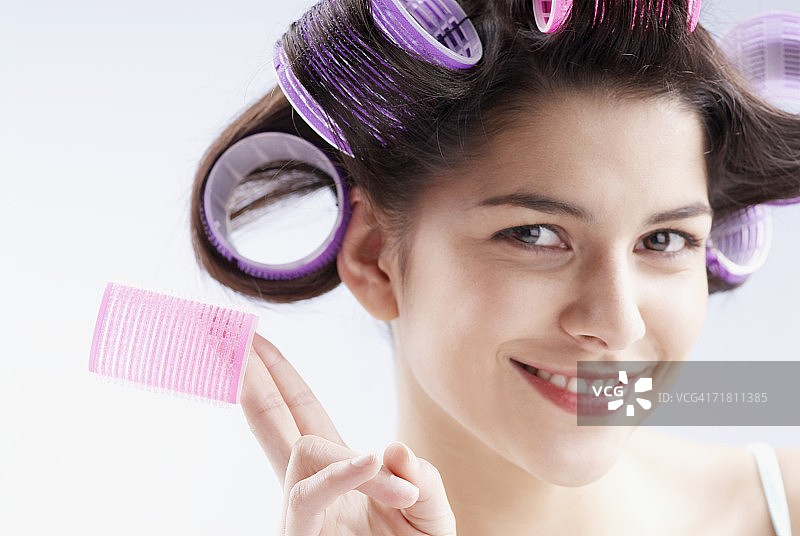 手持卷发棒的年轻女子肖像图片素材