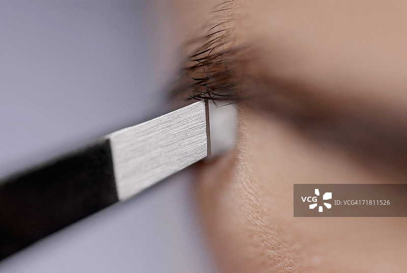 年轻女子拔眉毛的特写图片素材
