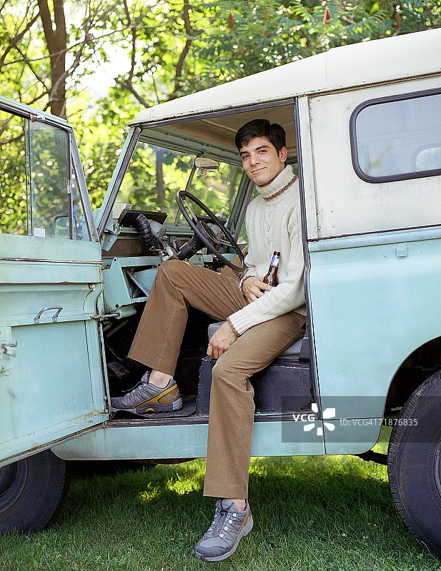 一日攀岩后，年轻男子在1964年的卡车里闲逛。图片素材