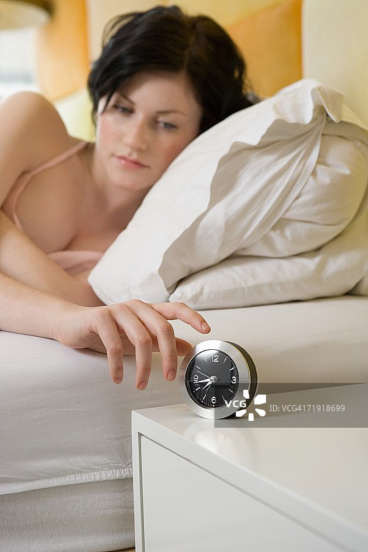 在床上打闹钟的年轻女人图片素材