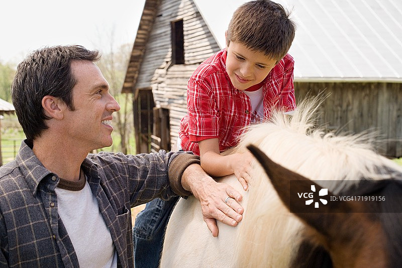 父亲协助儿子骑马图片素材
