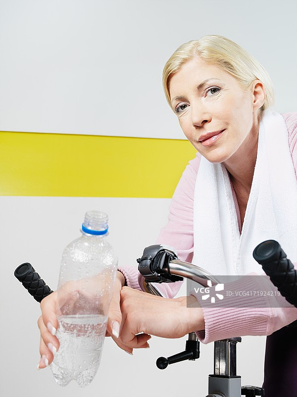 在健身俱乐部骑健身自行车的女人图片素材