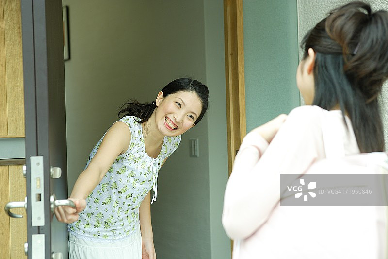 年轻女人在入口处迎接朋友图片素材