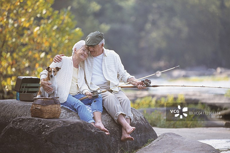 老年夫妇坐在岩石上钓鱼图片素材