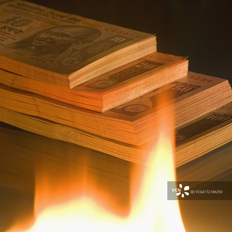 火焰旁不同面额的印度纸币的俯视角度照片图片素材