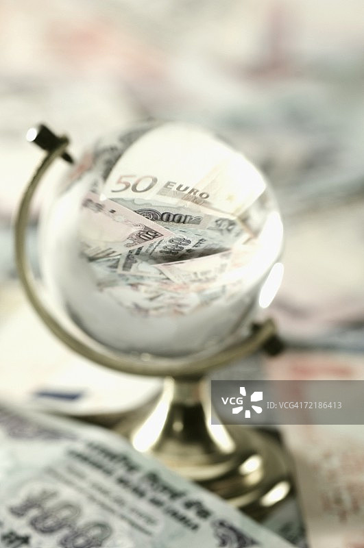 玻璃地球仪中的欧元和印度纸币高角度视图图片素材