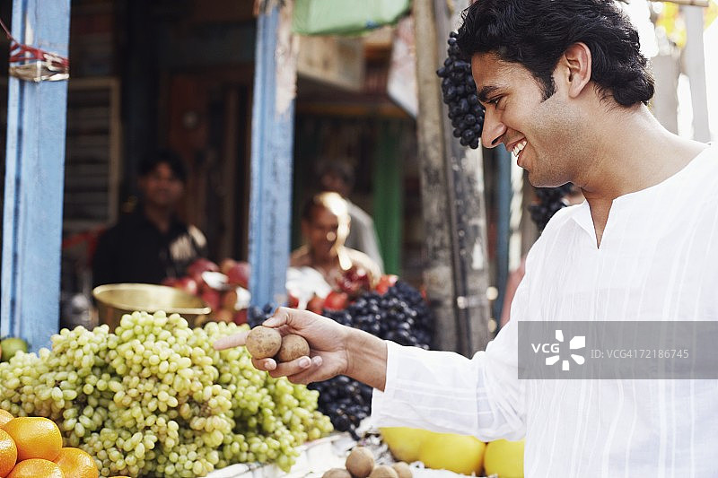 年轻男人侧面像，站在水果摊旁图片素材