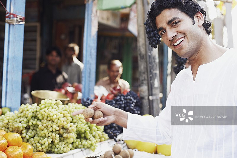 站在水果摊旁的年轻男子肖像图片素材