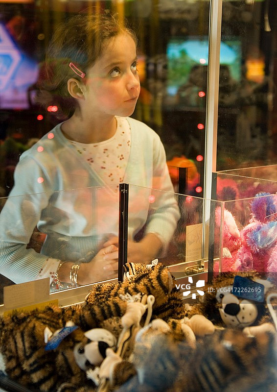 女孩透过玻璃看抓娃娃机图片素材