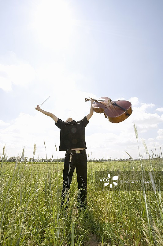 站在田野里拉大提琴的年轻男人图片素材
