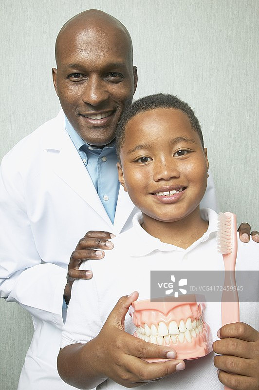 非洲男牙医与男孩拿着牙刷和牙齿模型图片素材