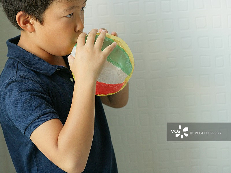 男孩吹纸气球的侧面轮廓照片图片素材