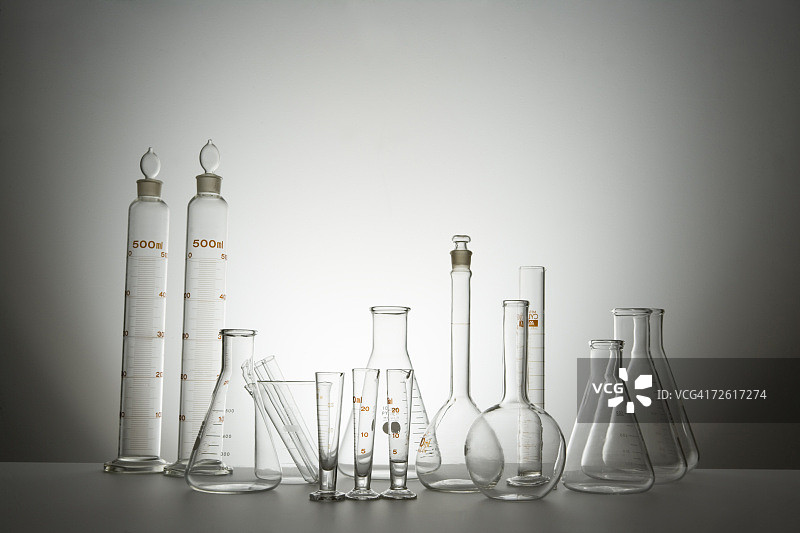 实验室瓶子和量筒正面图，灰色背景图片素材