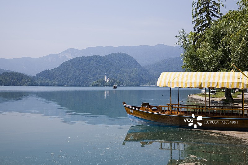 在岸边系泊的传统木制Pletnja舟，用于运送游客前往斯洛文尼亚布莱德湖岛上的圣玛丽升天教堂图片素材