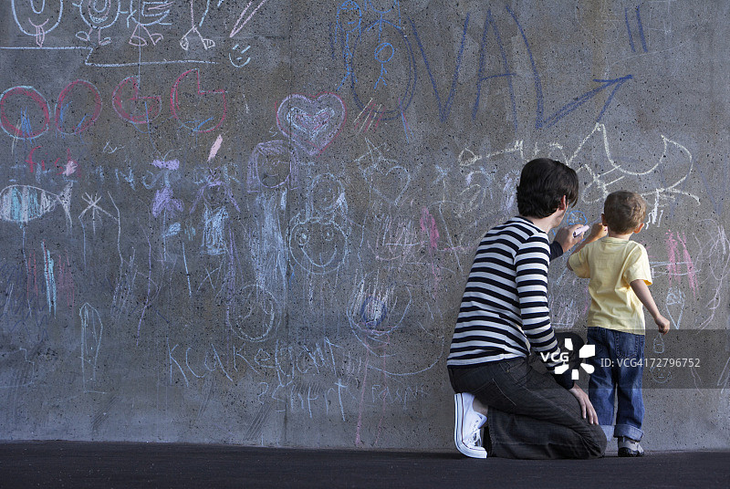 父亲和儿子（3-4岁）在墙上用粉笔写字图片素材
