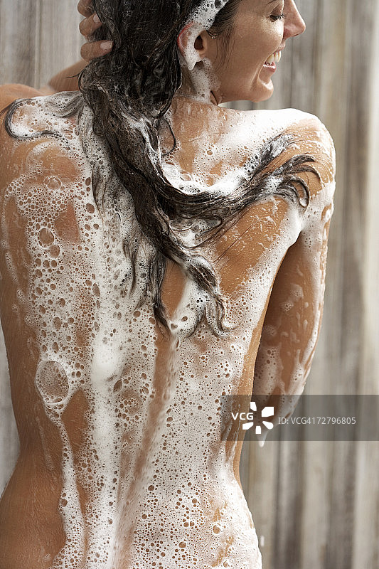 在淋浴中微笑、有肥皂泡的女人（后视图）图片素材