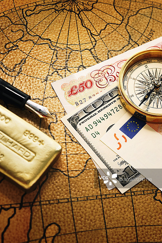 世界地图上的金元宝、笔、罗盘和货币图片素材