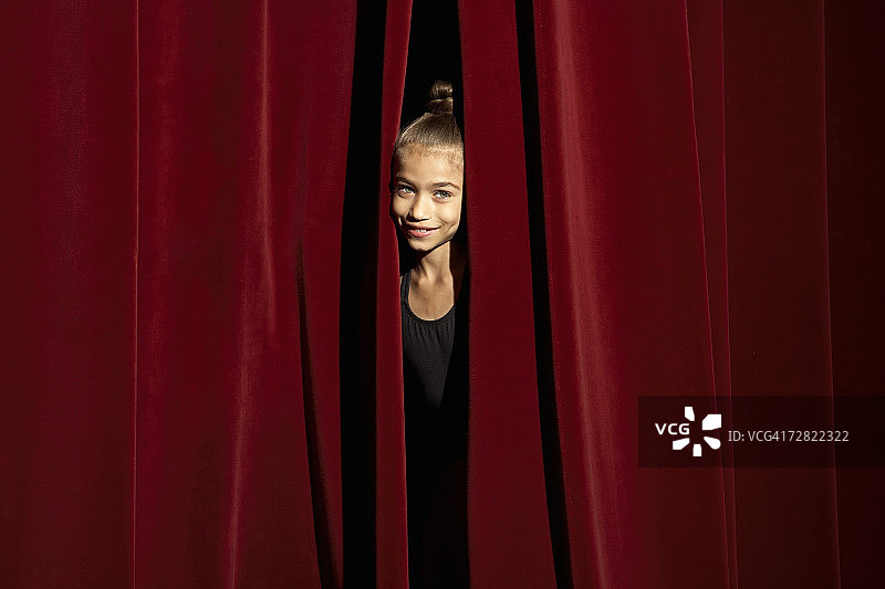 透过剧院窗帘偷看的女孩（6-7岁）肖像图片素材