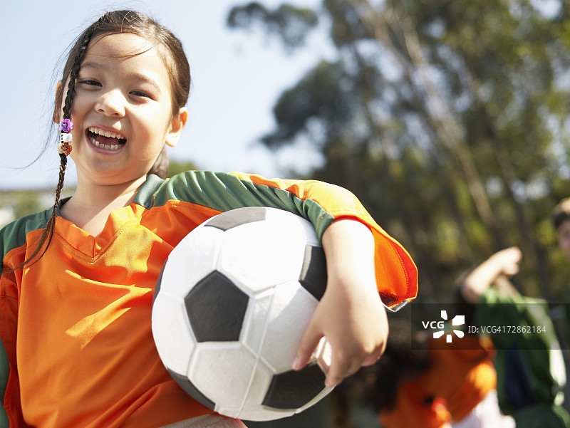 拿着足球的女孩（竖版，低角度）图片素材