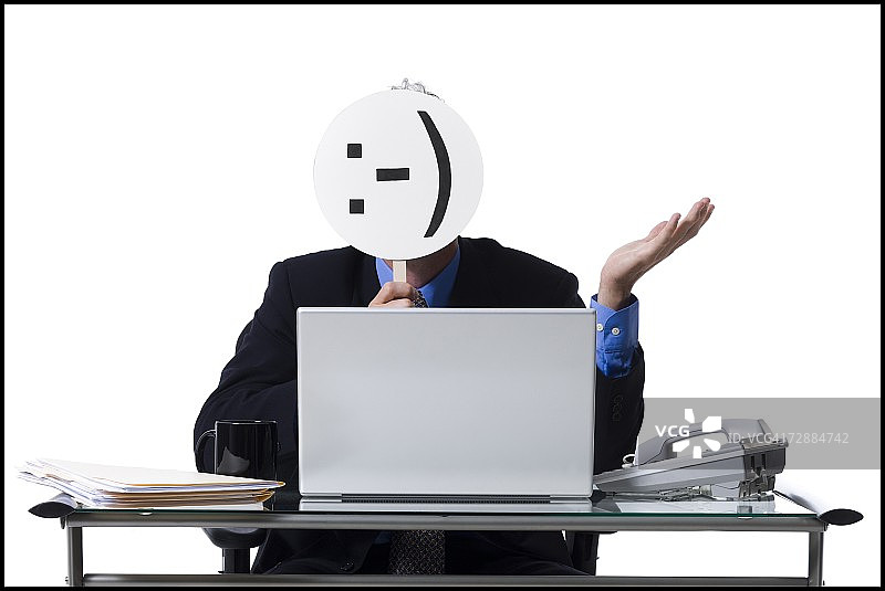 戴着笑脸面具和笔记本电脑的商人图片素材
