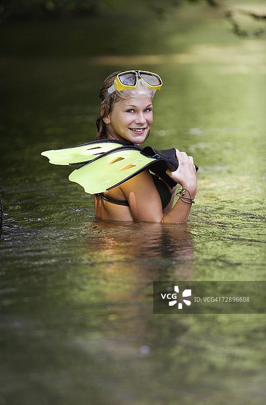 站在河里手拿脚蹼的少女（13-15岁）肖像图片素材