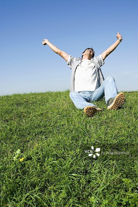 中年男人坐在公园里伸展身体，低角度视角图片素材