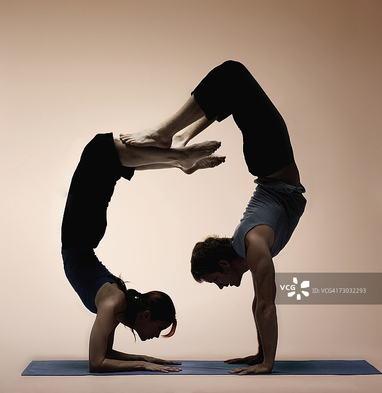 两名瑜伽学生展示高难度姿势，相互平衡，侧视图图片素材