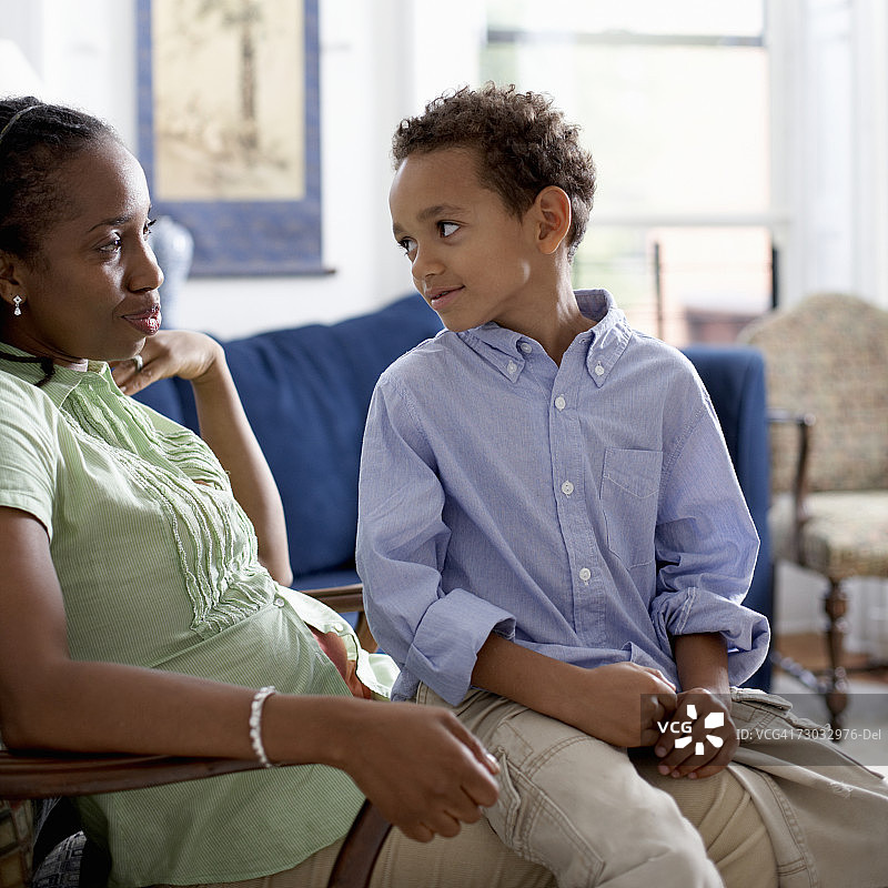 坐在扶手椅上，儿子（4-5岁）坐在腿上的女人图片素材