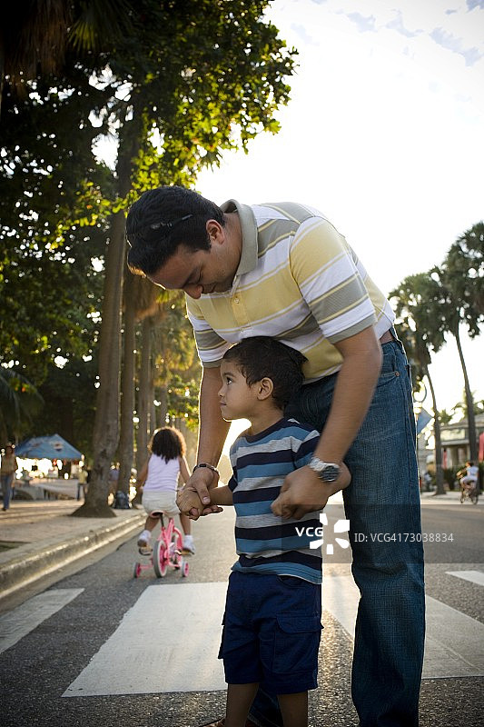 中年男人牵着儿子的手，在多米尼加共和国圣多明各的马雷孔图片素材