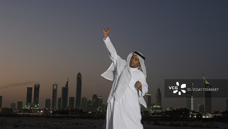 在迪拜城市背景下高兴跳跃的年轻阿拉伯男子图片素材