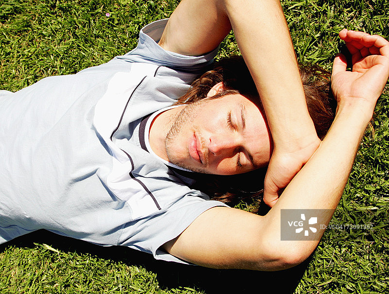 年轻男人躺在草地上，俯视图片素材