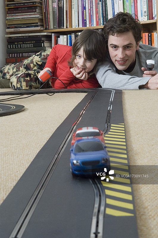 在客厅里和男人一起赛车的男孩（5-7岁）图片素材