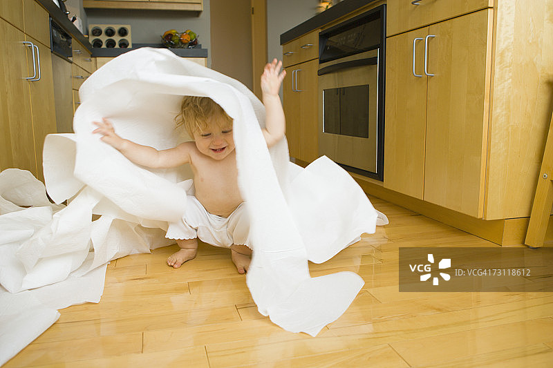 在厨房里扔纸巾卷的女婴（9-12个月）图片素材